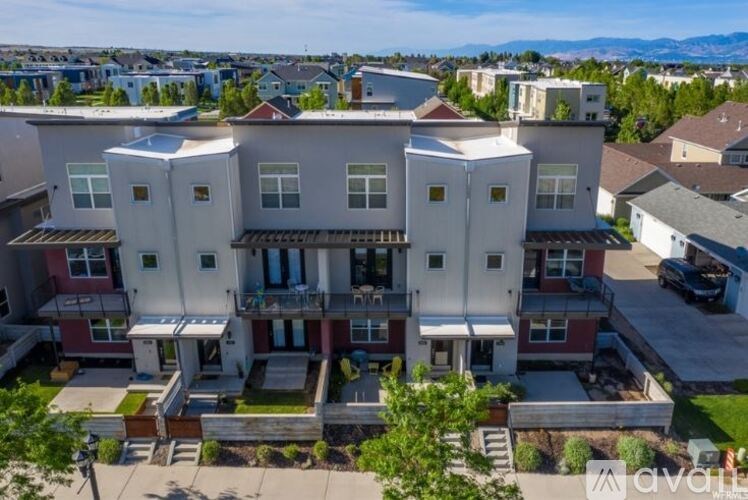 A large, multi-story building with a balcony on the second floor and a small garden in front.