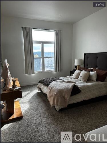 A bedroom with a large bed and a window overlooking a cityscape.