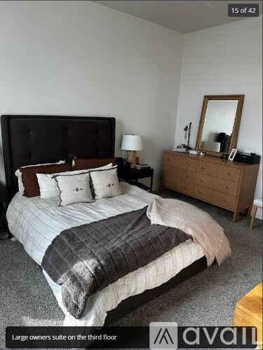 A bedroom with a large bed and a wooden dresser.