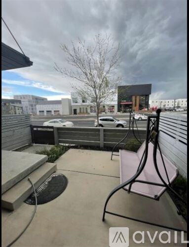 A balcony with a black metal railing and a pink cushion.