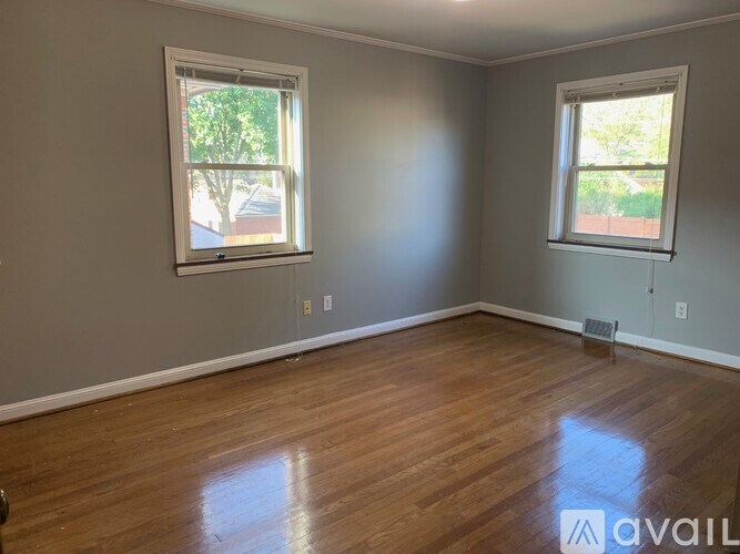 A room with wooden floors and two windows.