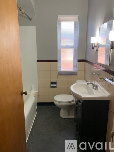 A bathroom with a toilet, sink, and mirror.