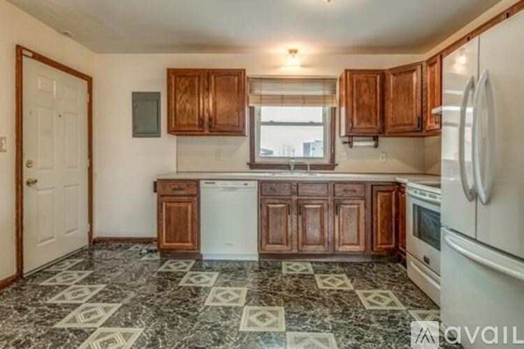 A kitchen with a black and white floor and wooden cabinets.
