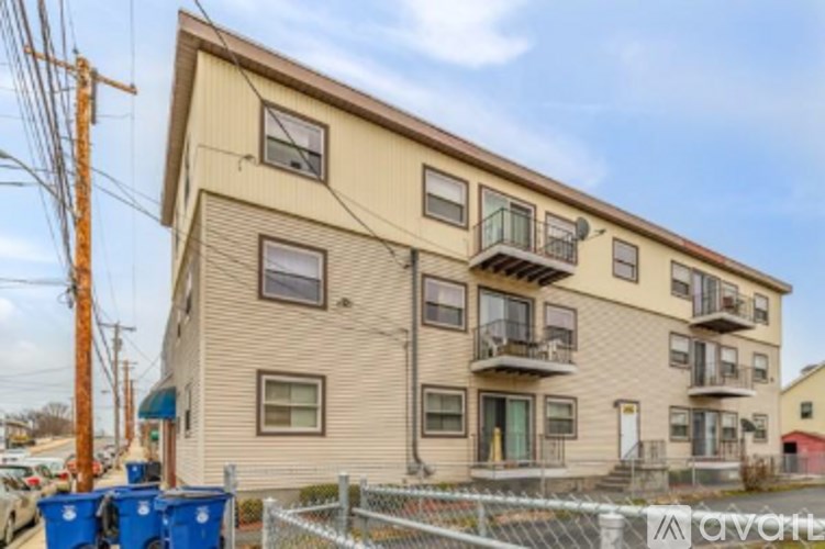 A two-story apartment building with a fenced parking area in front.