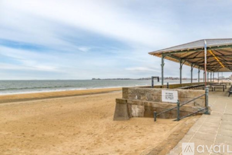 A beach scene with a shelter and a sign on the sand.