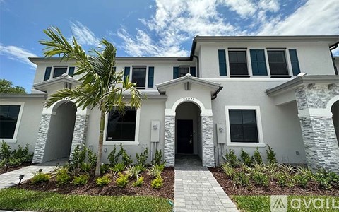 A white house with a palm tree in front.