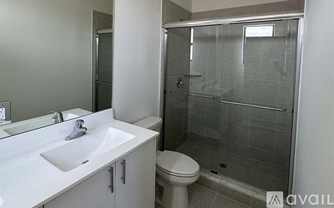 A bathroom with a white sink, toilet, and glass shower stall.