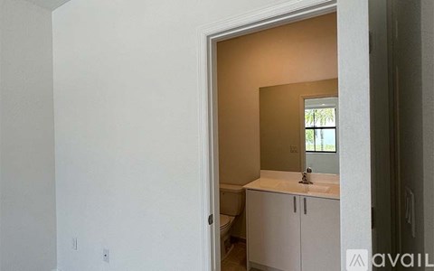 A bathroom with a sink and mirror is visible through an open door.