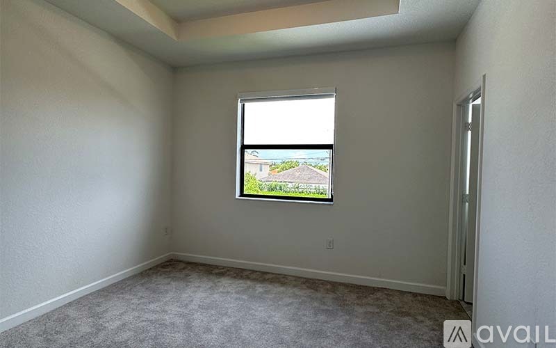 A room with a window showing a view of a house and trees.