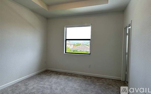 A room with a window showing a view of a house and trees.
