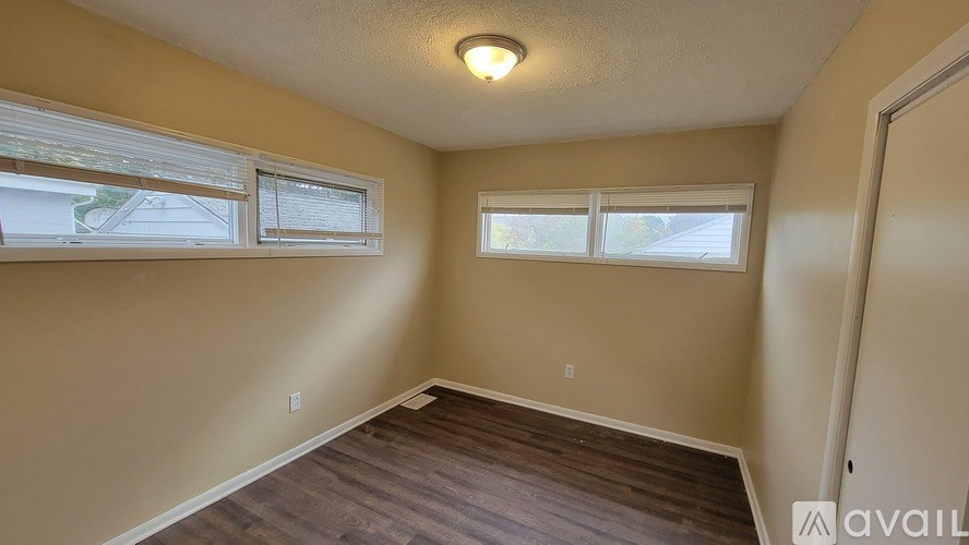 A room with a wooden floor and two windows.