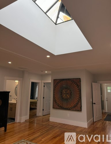 A room with a skylight and a large artwork on the wall.