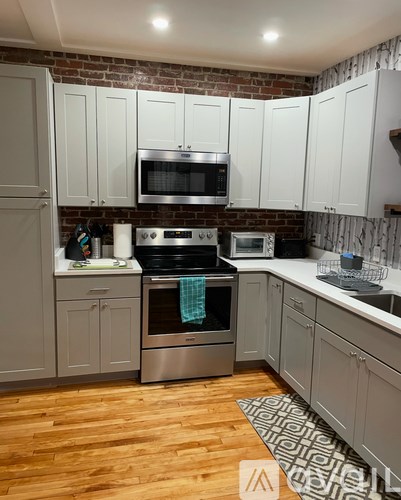 A kitchen with a brick wall and wooden floors.