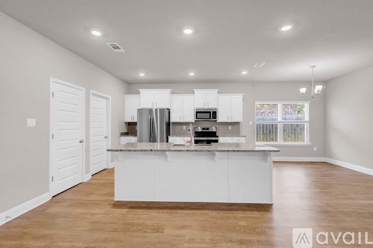 A modern kitchen with white cabinets and a wooden floor.
