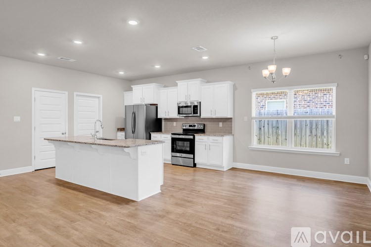 A kitchen with white cabinets and a wooden floor.