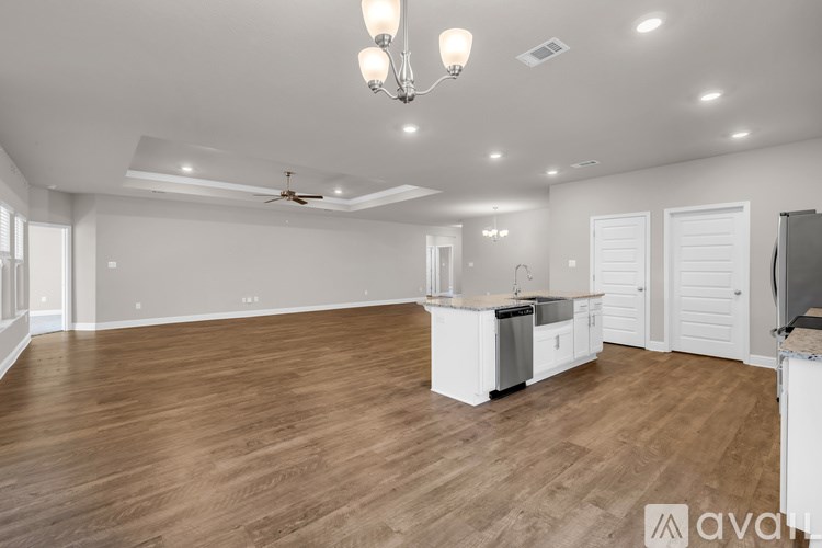 A spacious kitchen with wooden floors and white cabinetry.