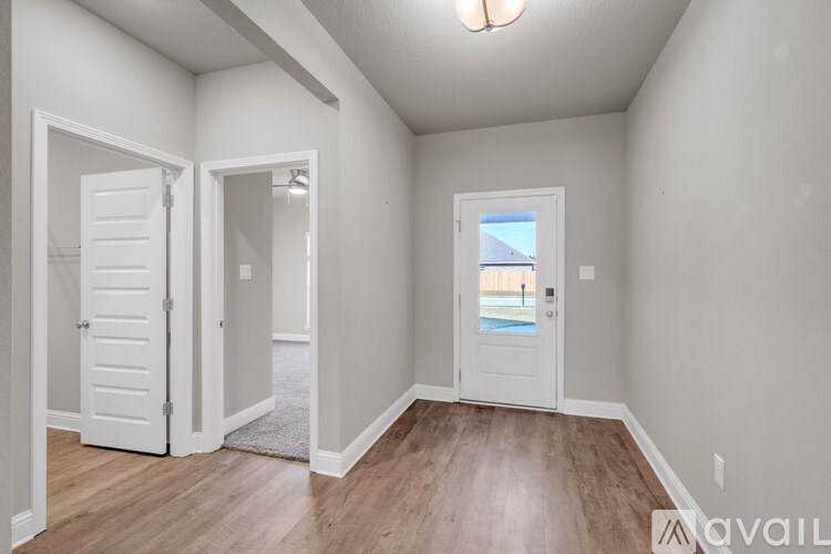 A room with a white door and a window with a view of a pool and a building.
