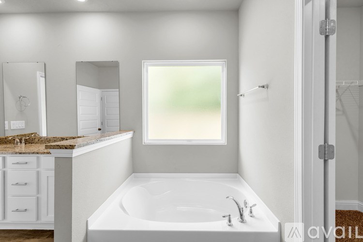A white bathroom with a large tub and a window.