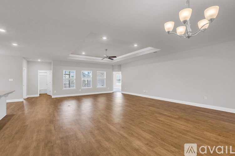 A spacious room with wooden floors and a chandelier.