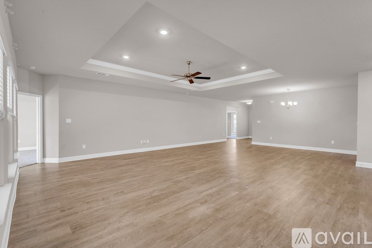 A spacious room with wooden flooring and a ceiling fan.