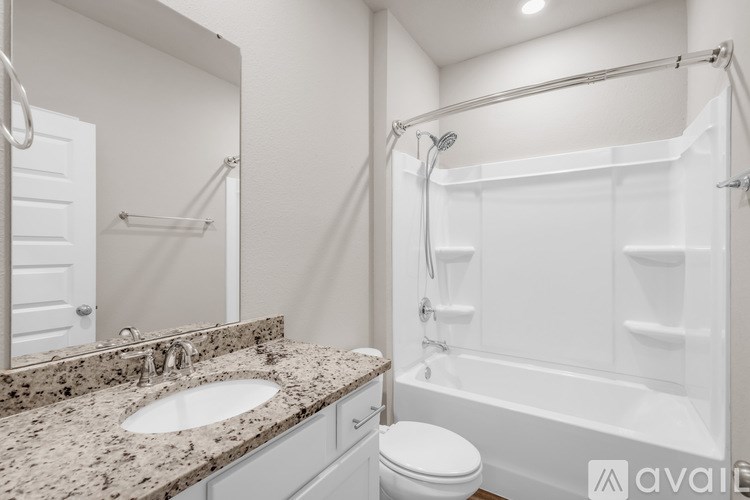 A bathroom with a marble countertop and white fixtures.