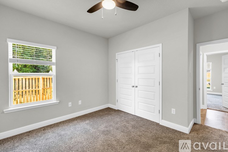 A room with a ceiling fan and a window with blinds.