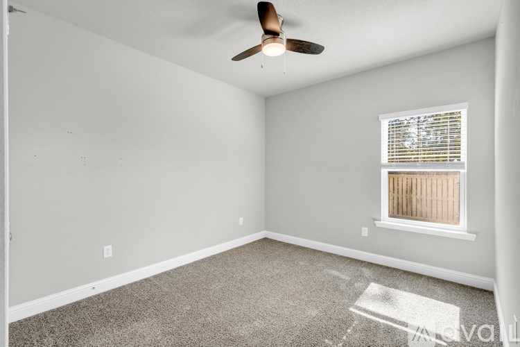 A room with a ceiling fan and a window with blinds.