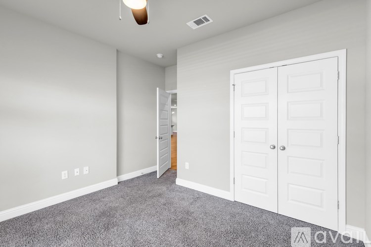 A room with a white door and a grey carpet.