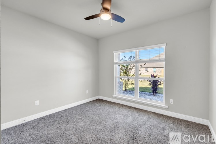 A room with a ceiling fan and a window showing a view of a garden outside.
