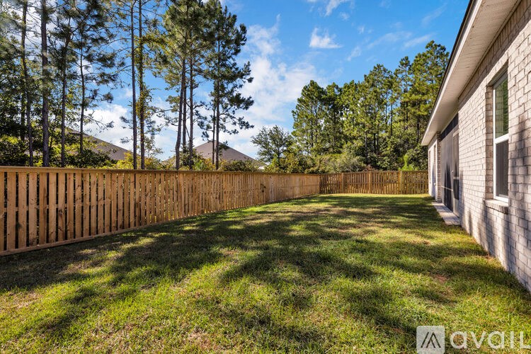 A backyard with a wooden fence and a house on the right side.
