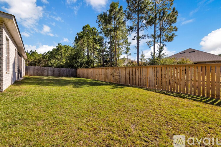 A backyard with a wooden fence and a house in the background.