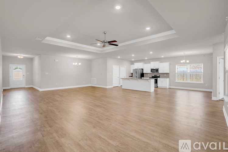 A spacious living room with a ceiling fan and hardwood flooring.