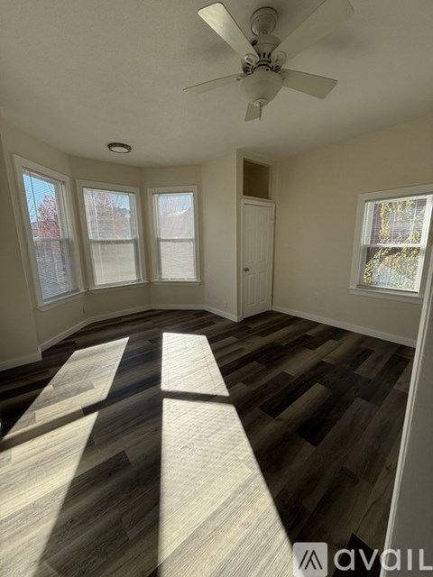 A room with a ceiling fan and wooden flooring.