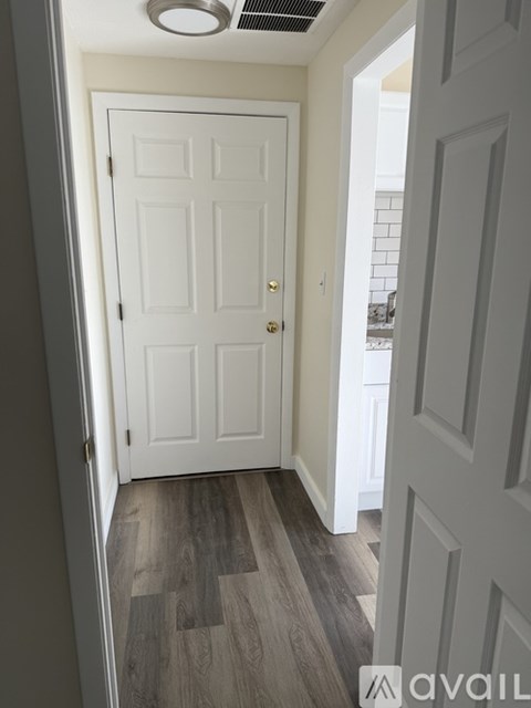 A white door with a silver handle is in a room with a wooden floor.
