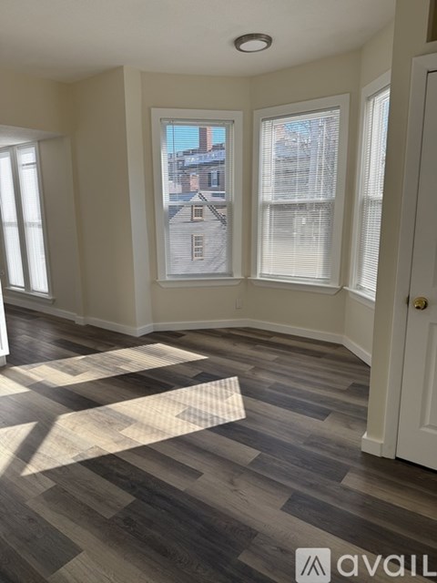A room with a wooden floor and a window showing a building outside.