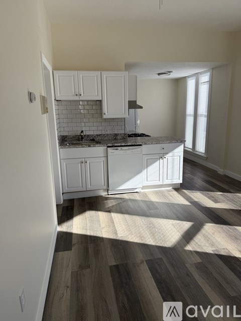 A kitchen with white cabinets and a wooden floor.