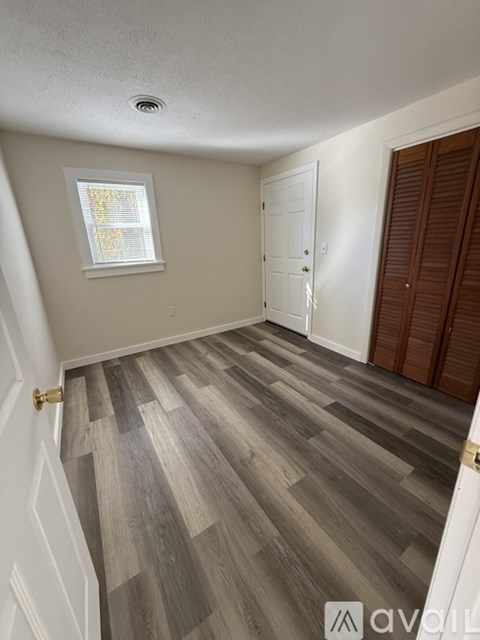A hallway with wooden flooring and white walls.