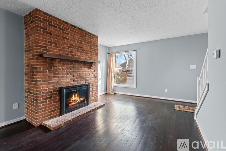 A brick fireplace in a room with wooden floors and a white ceiling.