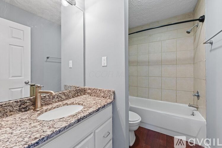 A bathroom with a marble countertop and a white bathtub.