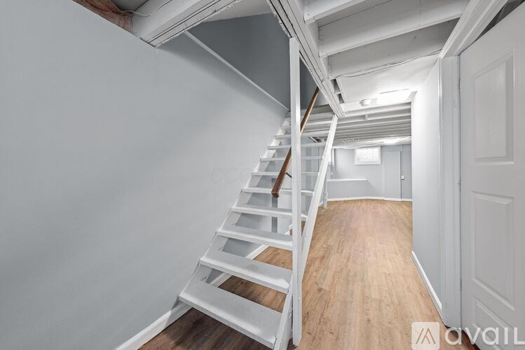 A white wooden staircase with a metal railing leads up to a second floor.