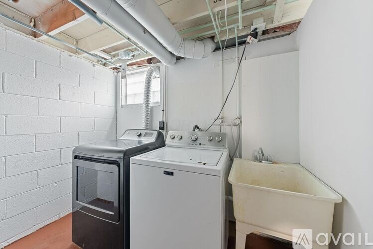 A small bathroom with a washing machine and a bathtub.