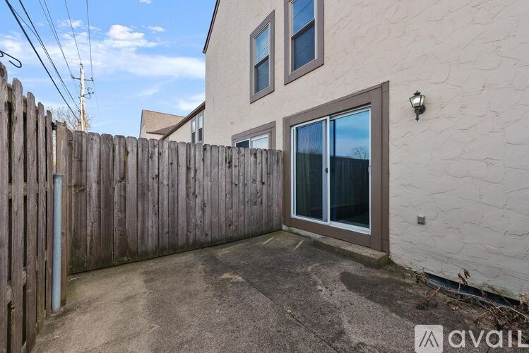 A backyard with a wooden fence and a house with a window and a door.