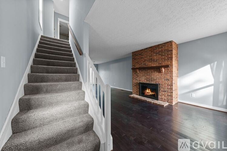 A staircase with a carpeted runner leads up to a brightly lit living room with a fireplace.