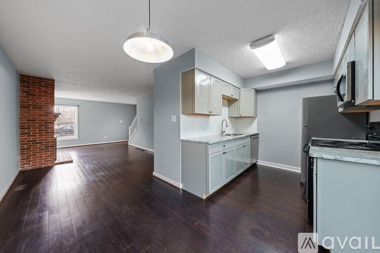 A kitchen with white cabinets and a brick wall.