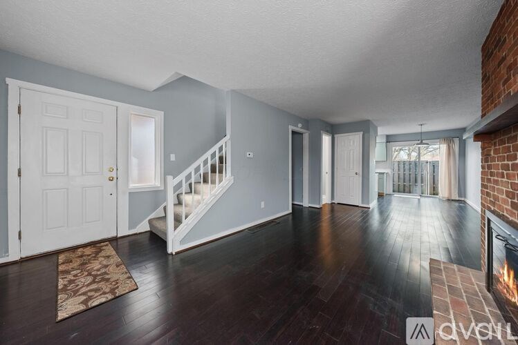 A living room with a fireplace and a staircase.