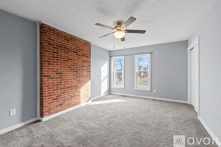 A room with a ceiling fan and a brick wall.