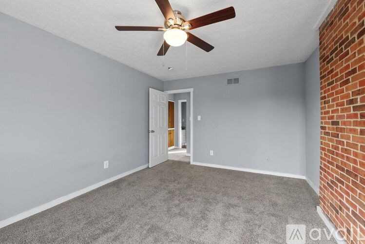 A room with a ceiling fan and a door leading to another room.