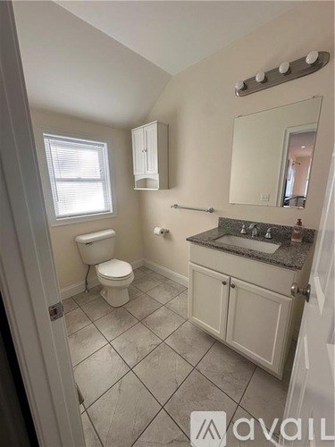 A bathroom with a toilet, sink, and mirror.