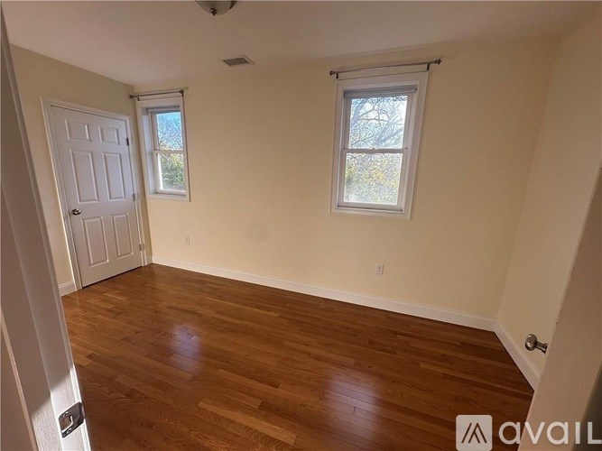 A room with wooden floors and two windows.