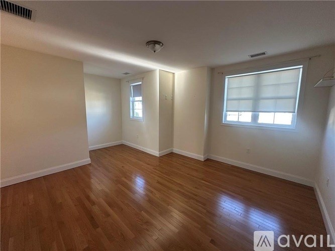 A room with wooden floors and two windows.